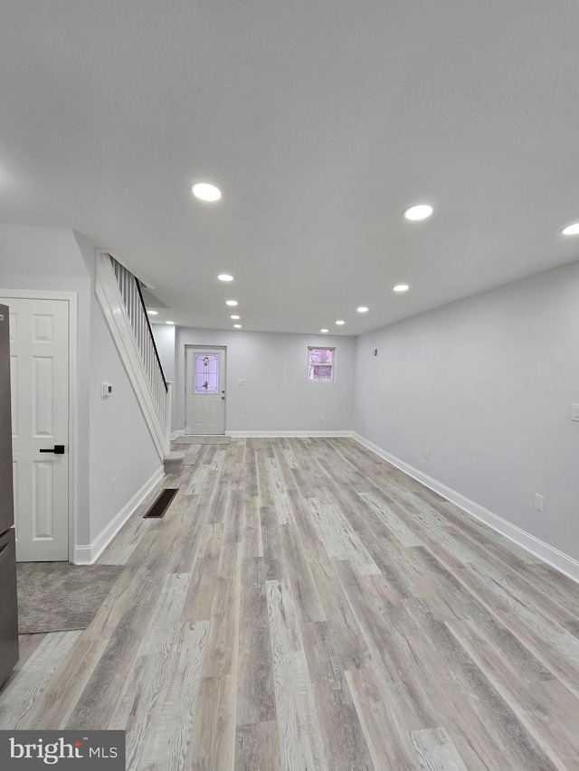 basement featuring stainless steel refrigerator and light hardwood / wood-style floors