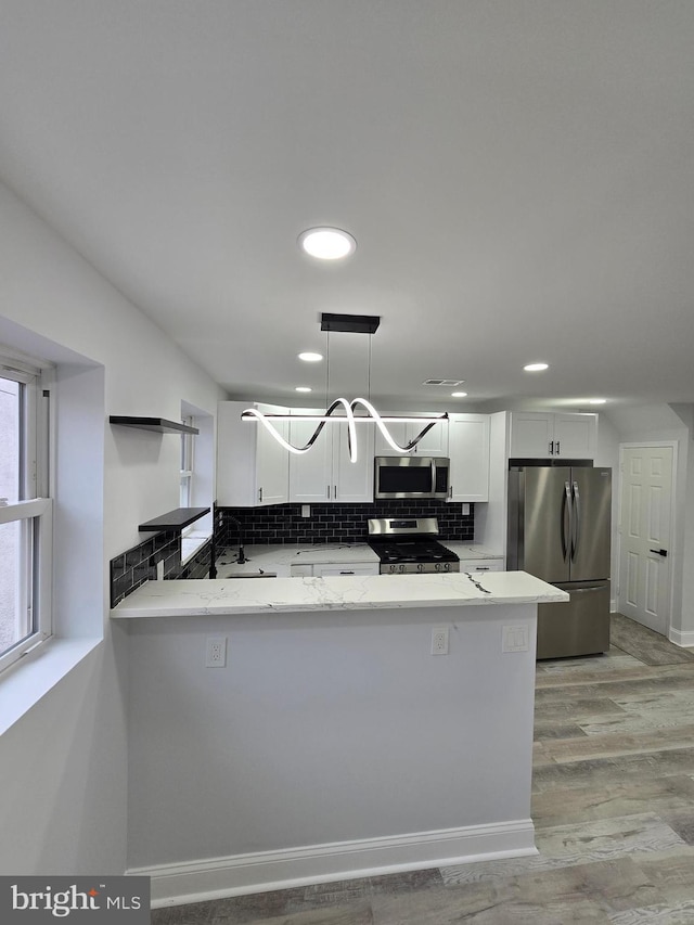 kitchen with white cabinetry, stainless steel appliances, decorative light fixtures, and kitchen peninsula