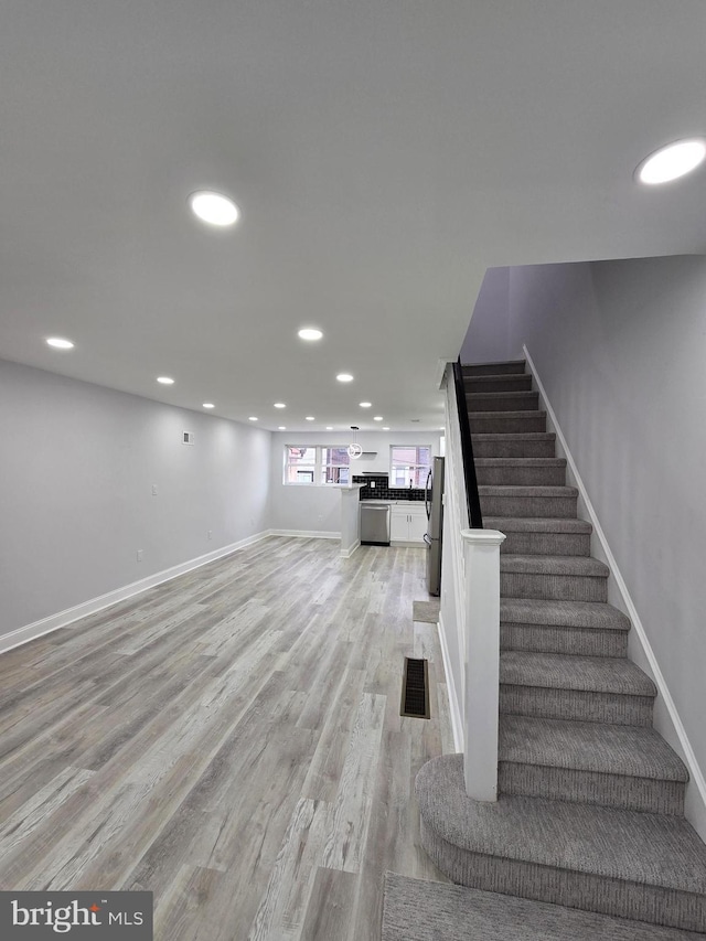 basement with stainless steel refrigerator and light wood-type flooring