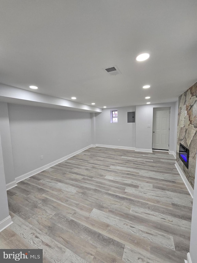 basement featuring light wood-type flooring and a fireplace