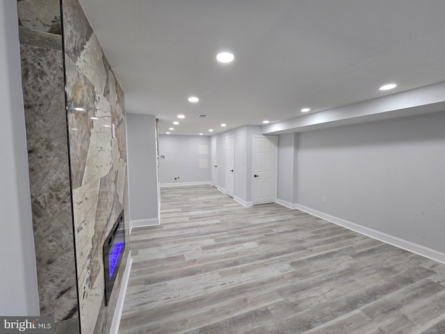 basement featuring light hardwood / wood-style floors and a large fireplace