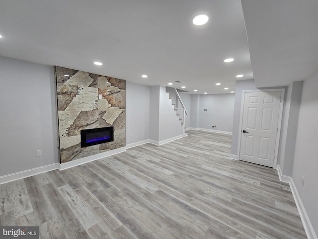 basement with a fireplace and light hardwood / wood-style flooring