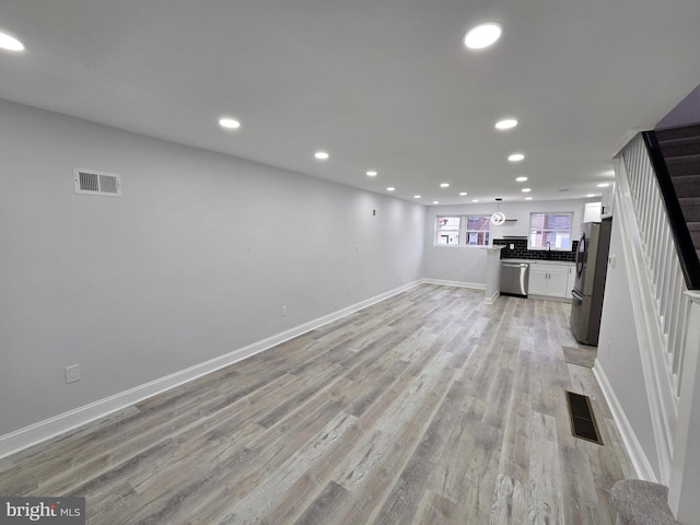 unfurnished living room featuring sink and light wood-type flooring