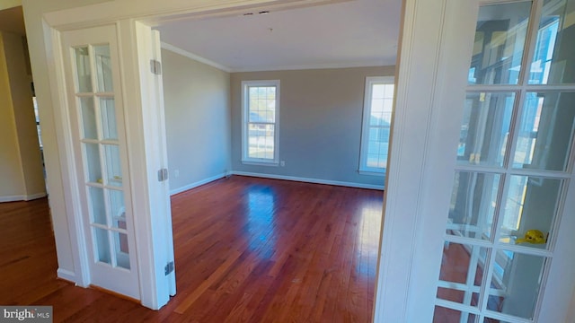 empty room with crown molding, dark hardwood / wood-style flooring, and french doors