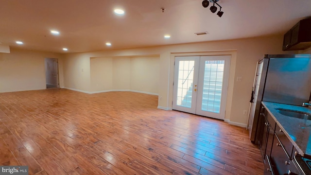 unfurnished living room with sink, light wood-type flooring, and french doors