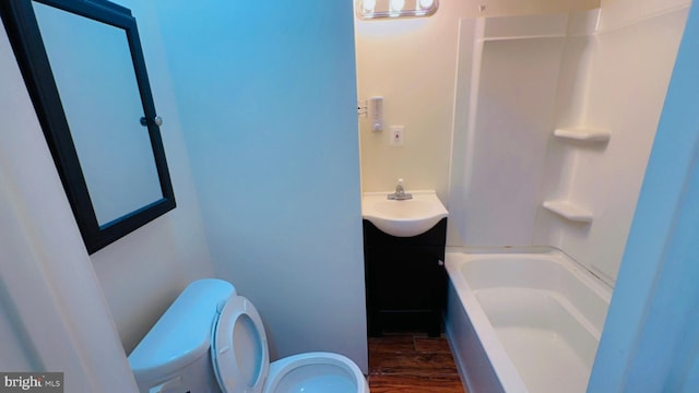 bathroom with vanity, a bath, hardwood / wood-style floors, and toilet