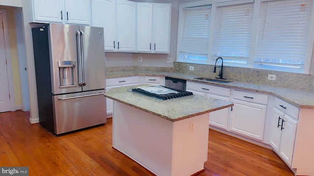 kitchen featuring sink, white cabinets, a center island, light stone countertops, and high end fridge