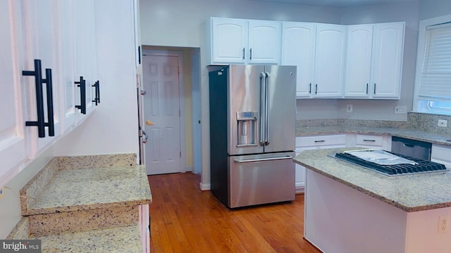 kitchen with white cabinetry, high end fridge, light stone counters, and light hardwood / wood-style flooring