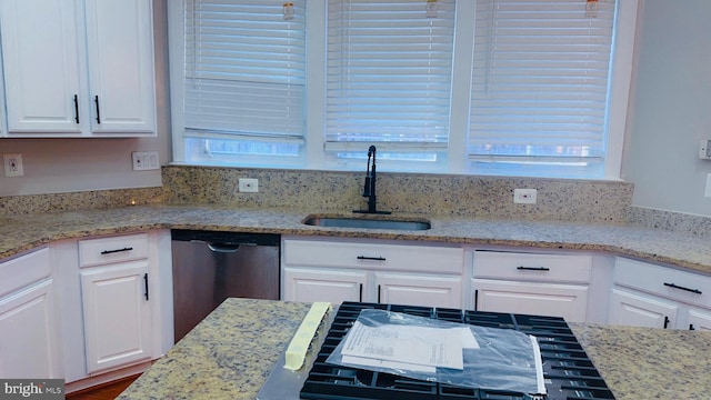 kitchen with white cabinetry, sink, stainless steel dishwasher, and light stone counters