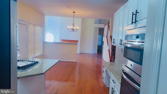 kitchen with pendant lighting, white cabinetry, light stone counters, a notable chandelier, and light hardwood / wood-style floors