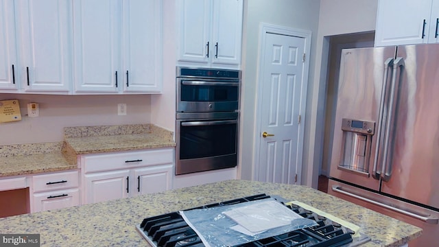 kitchen with light stone countertops, white cabinetry, and appliances with stainless steel finishes