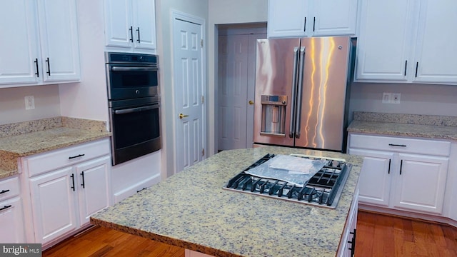 kitchen with light stone counters, white cabinetry, appliances with stainless steel finishes, and dark hardwood / wood-style floors