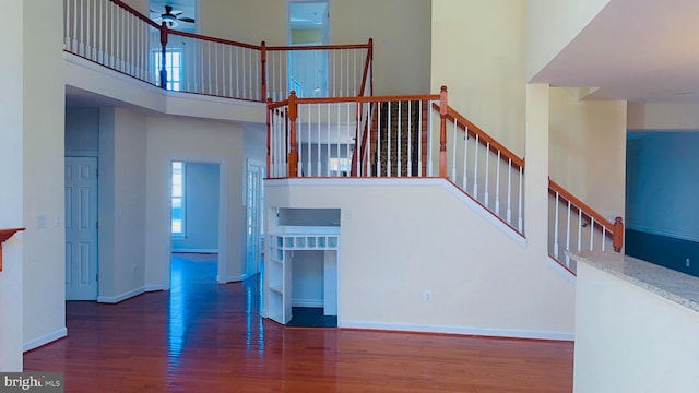 unfurnished living room with ceiling fan, a towering ceiling, and dark hardwood / wood-style flooring