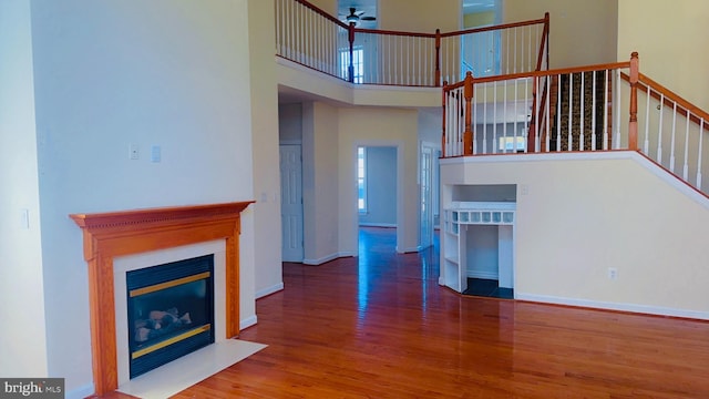 unfurnished living room featuring hardwood / wood-style flooring and a towering ceiling