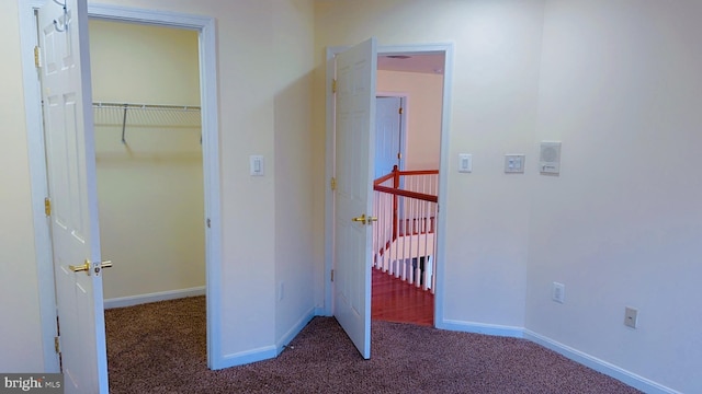 corridor featuring dark colored carpet