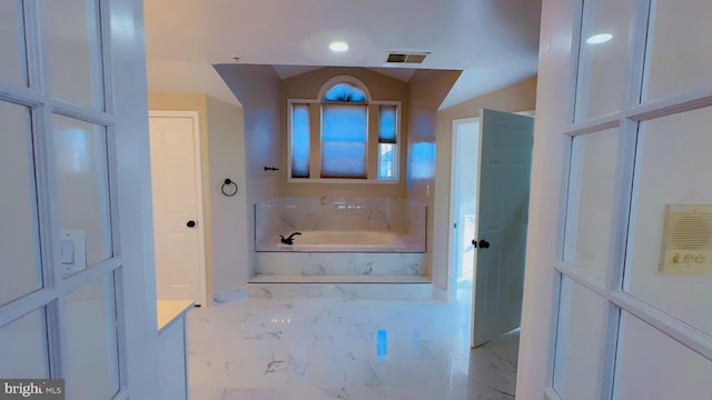 bathroom with vaulted ceiling and a tub