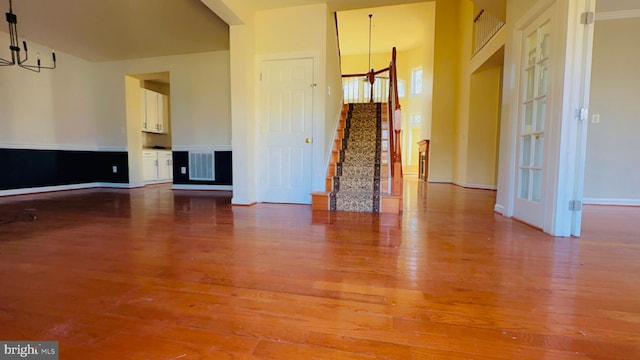 empty room with wood-type flooring and a chandelier