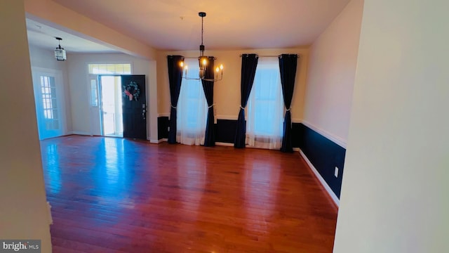 empty room featuring hardwood / wood-style flooring and a chandelier