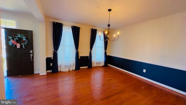 unfurnished dining area with hardwood / wood-style floors and an inviting chandelier