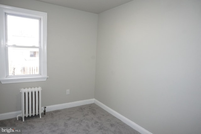 spare room featuring radiator heating unit and light colored carpet