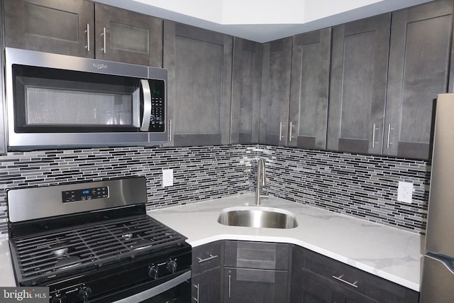 kitchen featuring sink, appliances with stainless steel finishes, dark brown cabinets, tasteful backsplash, and light stone countertops