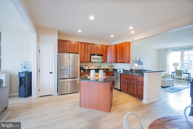 kitchen with sink, a center island, light wood-type flooring, kitchen peninsula, and stainless steel appliances