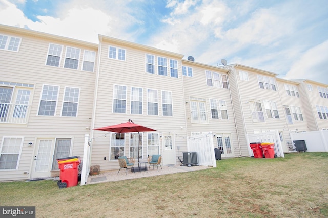 rear view of property featuring a yard, cooling unit, and a patio area