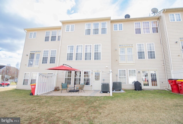 rear view of property with central AC unit, a lawn, and a patio area