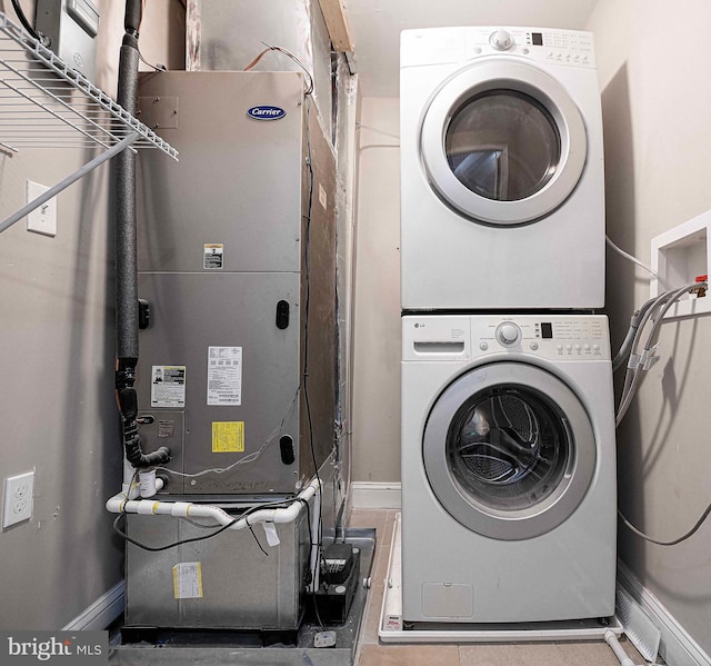 laundry room with heating unit and stacked washer / drying machine