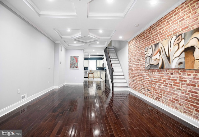 unfurnished living room featuring wood-type flooring, brick wall, coffered ceiling, and crown molding