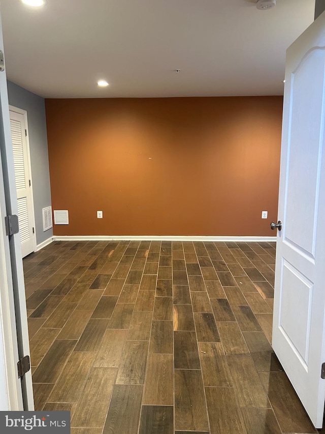 basement featuring wood finish floors, visible vents, and baseboards