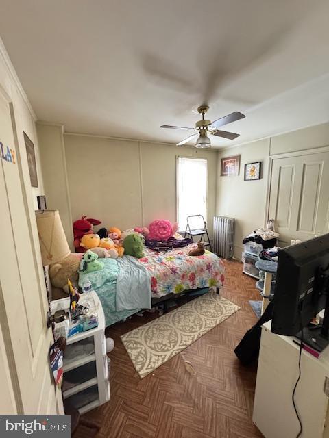 bedroom with ceiling fan, dark parquet flooring, and radiator heating unit