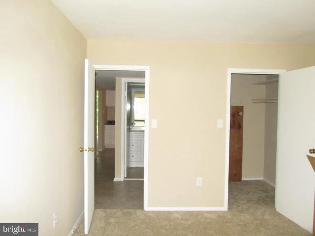 unfurnished bedroom with carpet, a spacious closet, and a closet