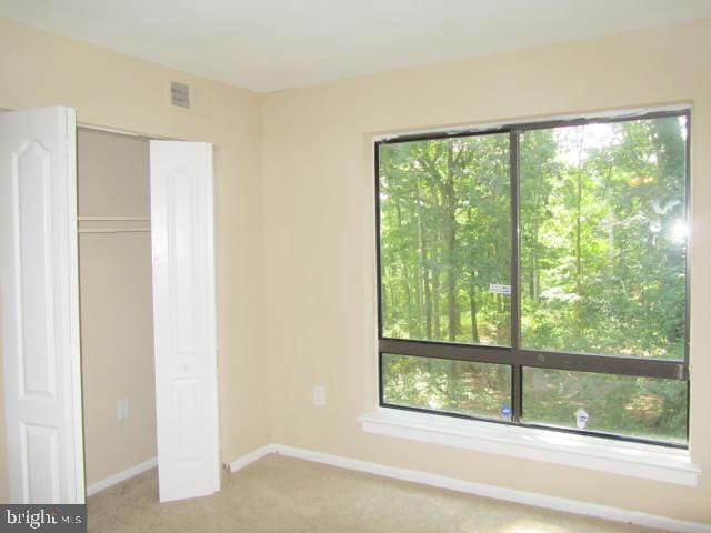 unfurnished bedroom featuring light colored carpet and a closet