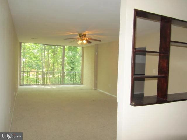 carpeted spare room featuring ceiling fan