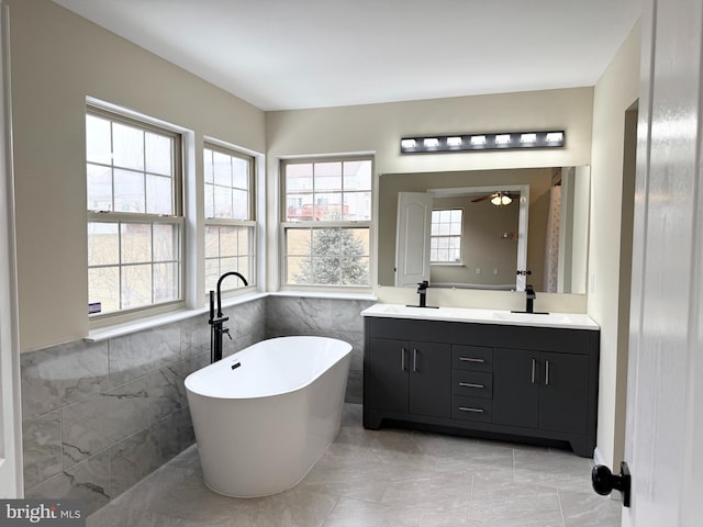 bathroom featuring vanity, a bath, and tile walls