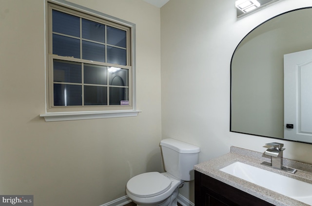 bathroom with toilet, vanity, and baseboards