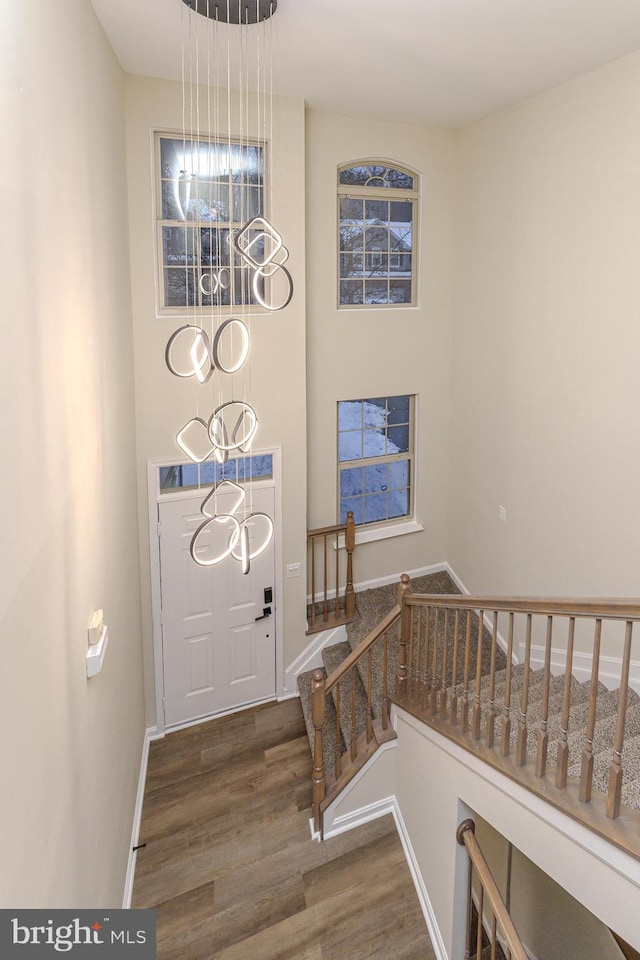 foyer entrance with a chandelier, stairway, baseboards, and wood finished floors