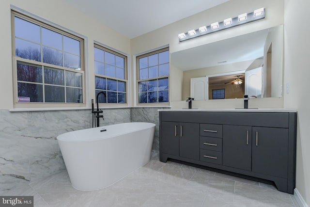 bathroom featuring double vanity, a freestanding tub, ceiling fan, and a sink