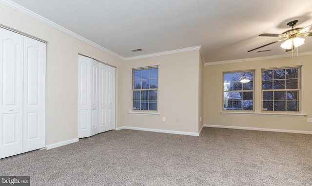 unfurnished bedroom with crown molding, carpet, visible vents, and two closets