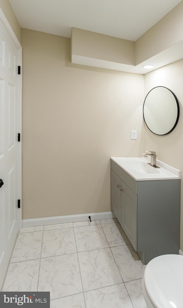 half bath with baseboards, toilet, marble finish floor, and vanity