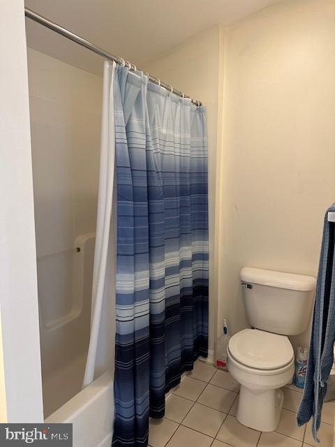 bathroom with shower / bath combo, tile patterned floors, and toilet