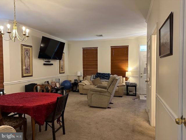 carpeted dining area with crown molding and a notable chandelier