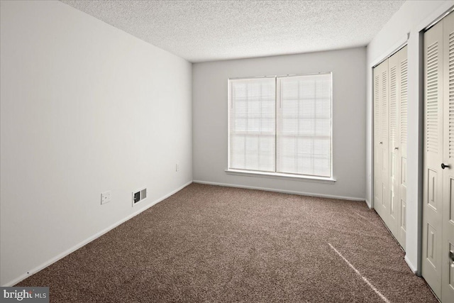 unfurnished bedroom featuring multiple closets, carpet, and a textured ceiling