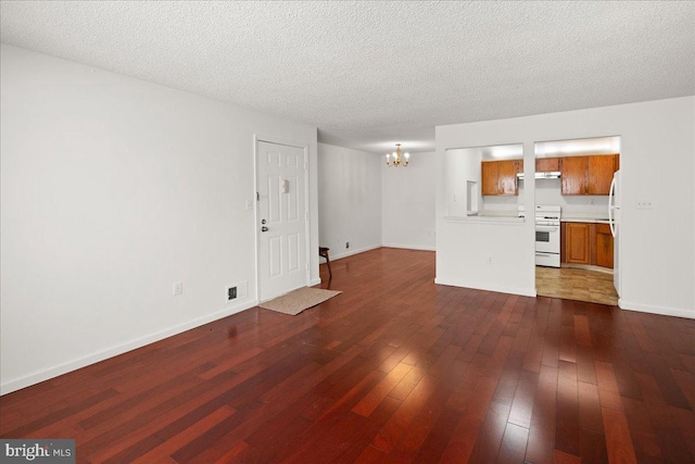 unfurnished living room with a textured ceiling, a notable chandelier, and dark hardwood / wood-style flooring