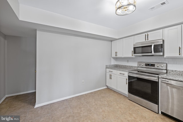 kitchen featuring backsplash, light stone countertops, white cabinets, and appliances with stainless steel finishes