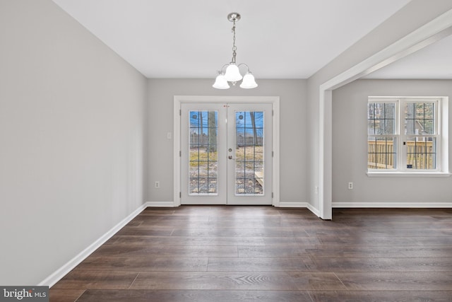 unfurnished dining area with dark hardwood / wood-style floors, a notable chandelier, and french doors