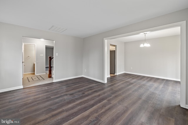 unfurnished room featuring dark hardwood / wood-style flooring and an inviting chandelier