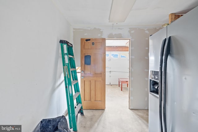 interior space featuring stainless steel fridge with ice dispenser and concrete flooring