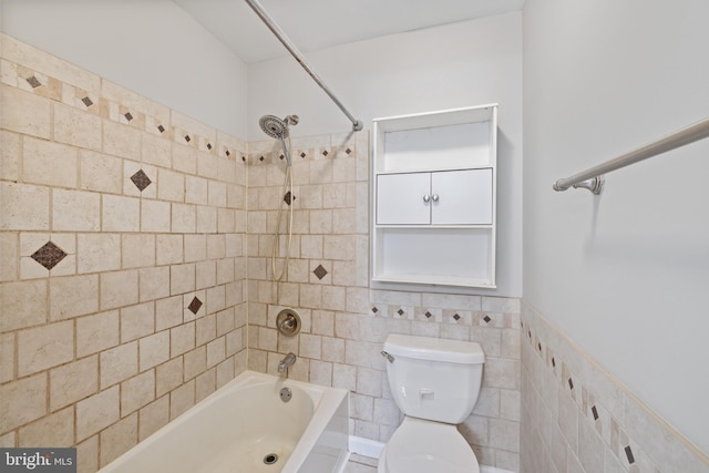 bathroom with tile walls, tiled shower / bath combo, and toilet